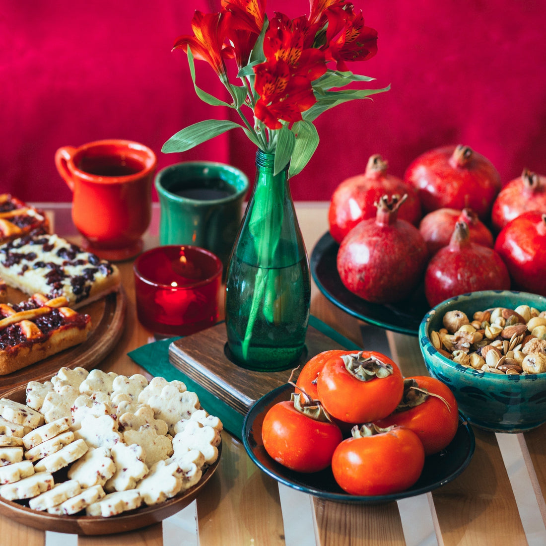 Persian Yalda celebration table with pomegranates, persimmons, nuts, sweets, and red decorations symbolizing light, warmth, and cultural tradition.