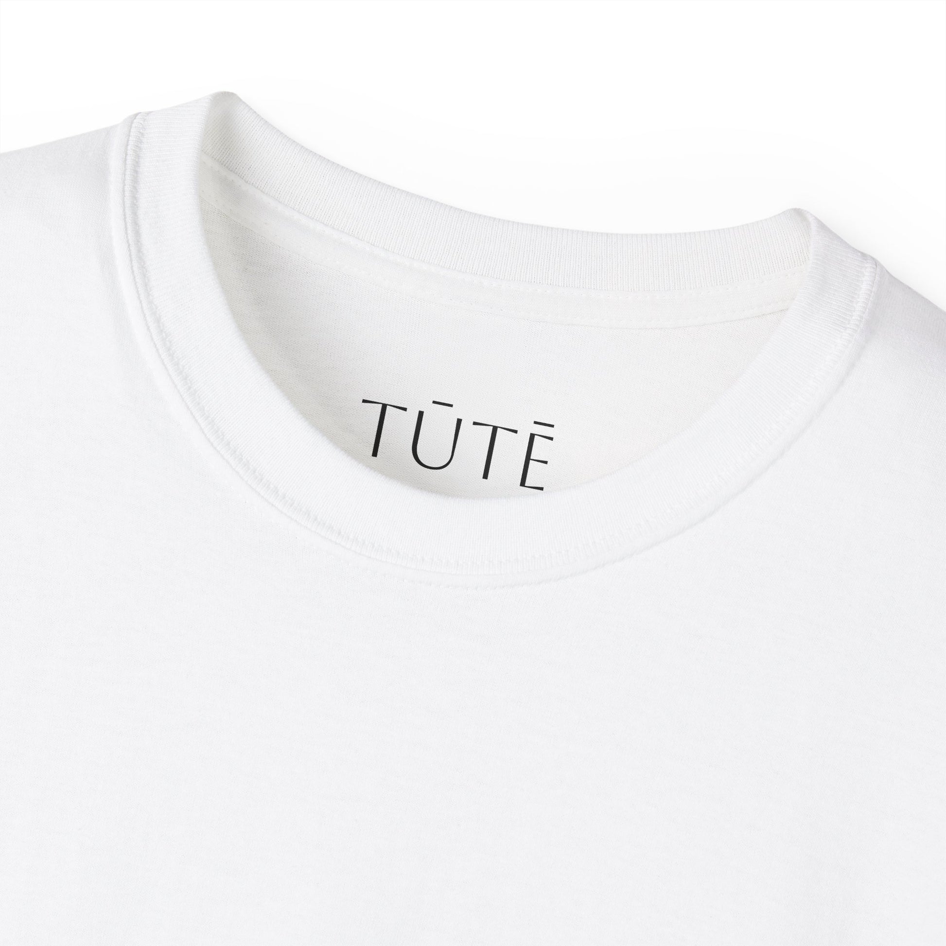 Close-up of a white shirt with 'TUTE' branding on a white background